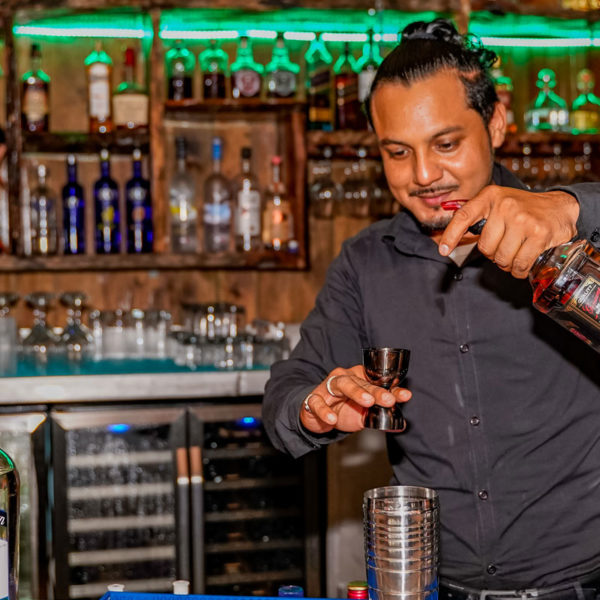 Bartender pouring a drink behind the best Caye Caulker bar at El Portal at the Split