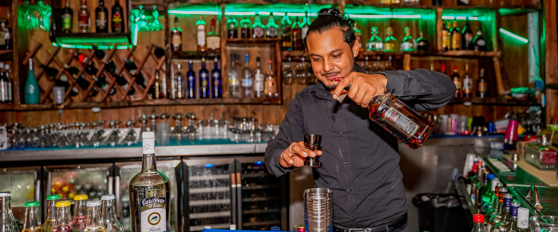 Bartender pouring a drink behind the best Caye Caulker bar at El Portal at the Split